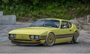Gul vw sp2 med guldfärgade fälgar står på grusväg.