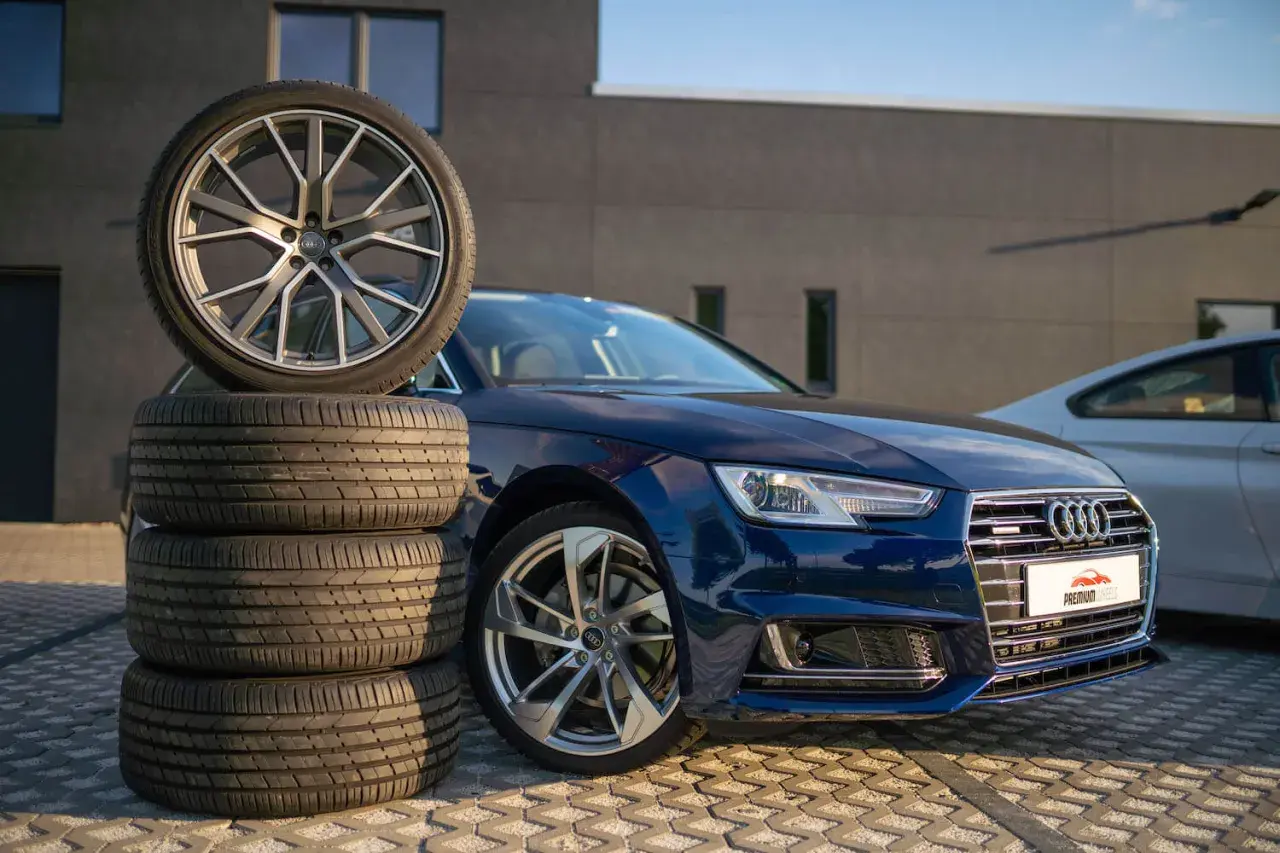 Mörkblå Audi A4 B9 med en stapel däck och en fälg.