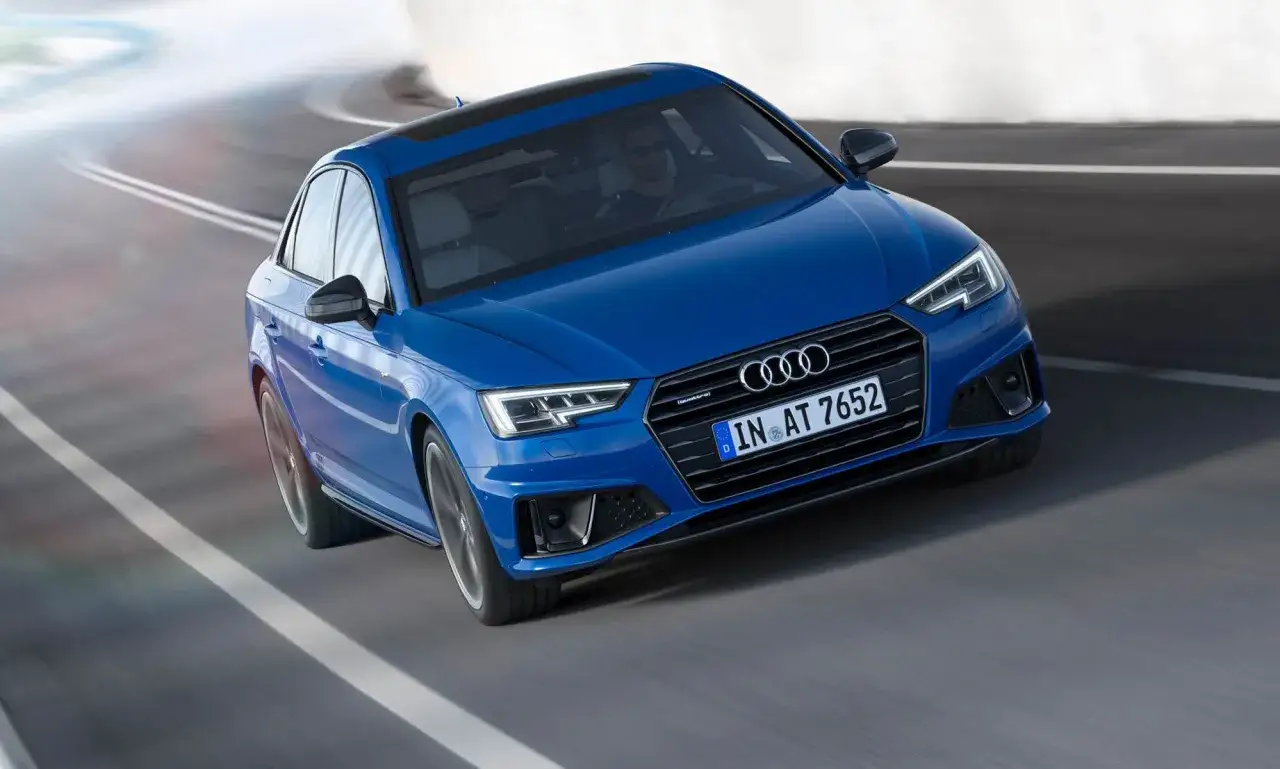 Bl&aring; Audi A4 B9 k&ouml;r p&aring; en kurvig v&auml;g med suddiga vita linjer.