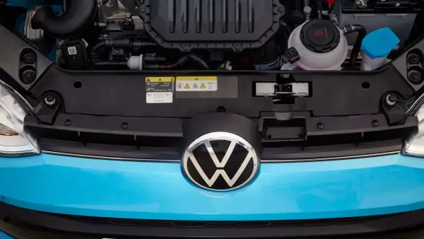 Motorutrymme på en blå Volkswagen. En etikett visar information om olja och gas, vilket kan vara relevant vid problem med en begagnad gasbil.